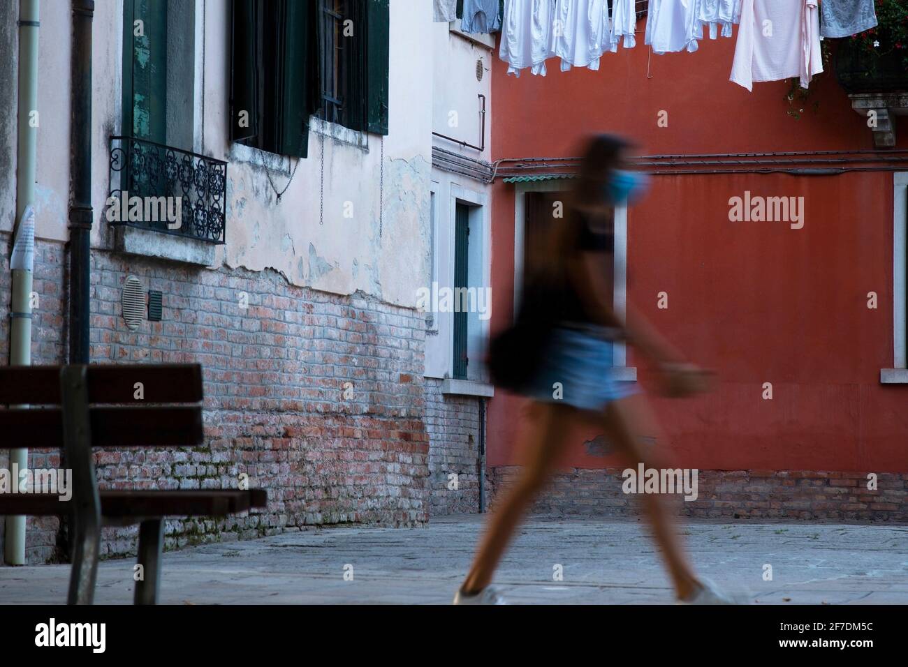 Jeune femme marchant le long d'une rue avec masque à Venise, Italie pendant la pandémie COVID-19 Banque D'Images