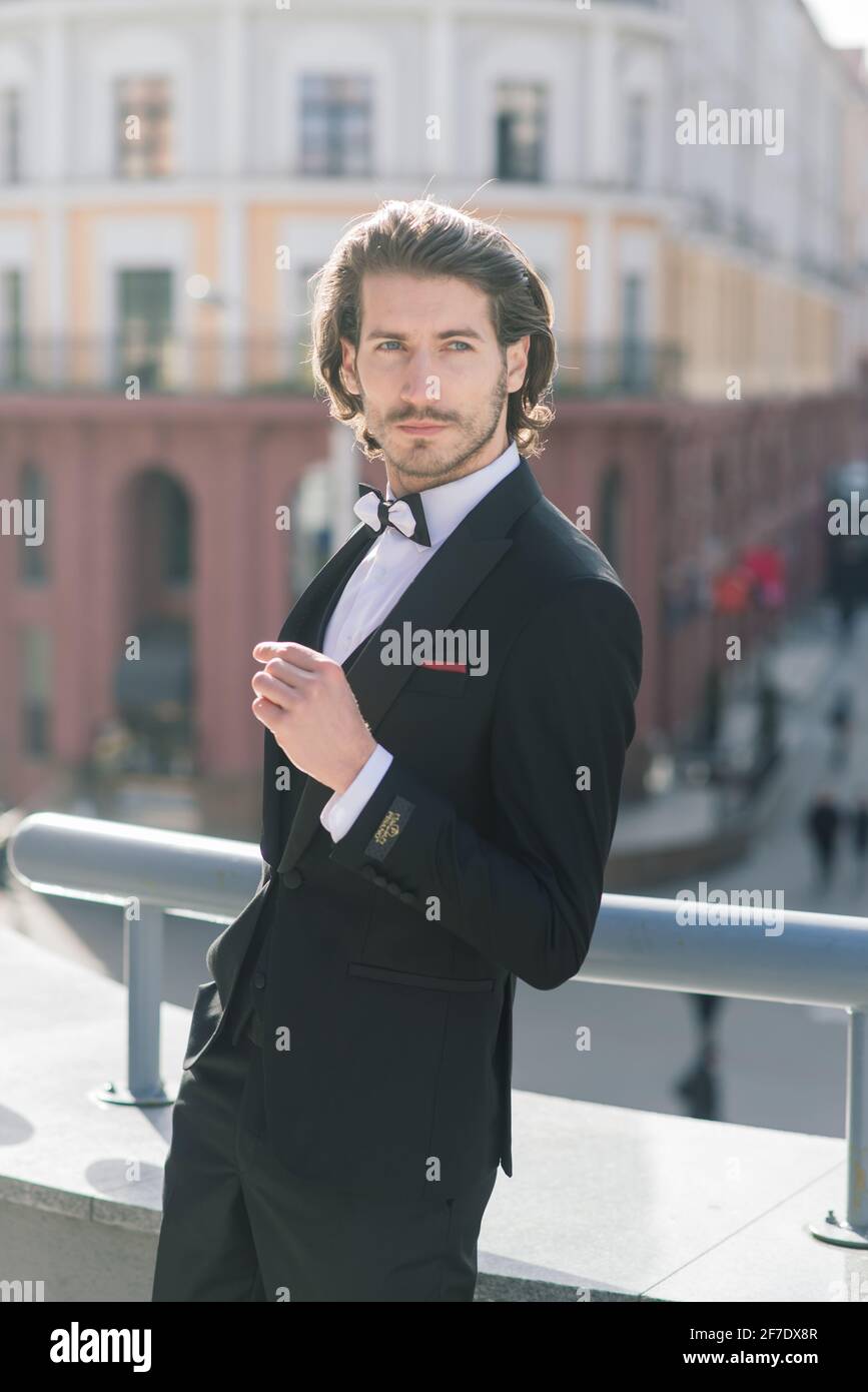 Beau homme élégant avec barbe, portant une veste de costume et une chemise,  en plein air dans la rue de la ville. Détails de la tenue classique  élégante pour Homme Photo Stock -