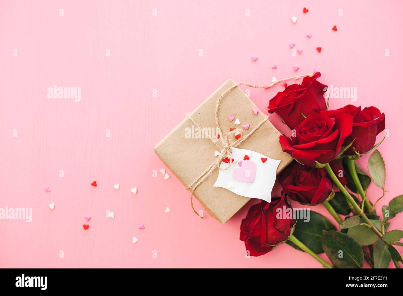 Arrière-plan pour la journée des femmes - fond rose rouge avec papier cadeau brun et confetti en forme de coeur sur fond rose. Saint-Valentin et mères d Banque D'Images