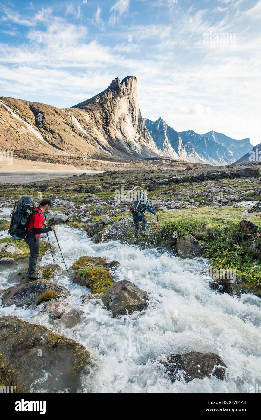 Backpackers traverser la rivière tout en traversant un col de montagne. Banque D'Images