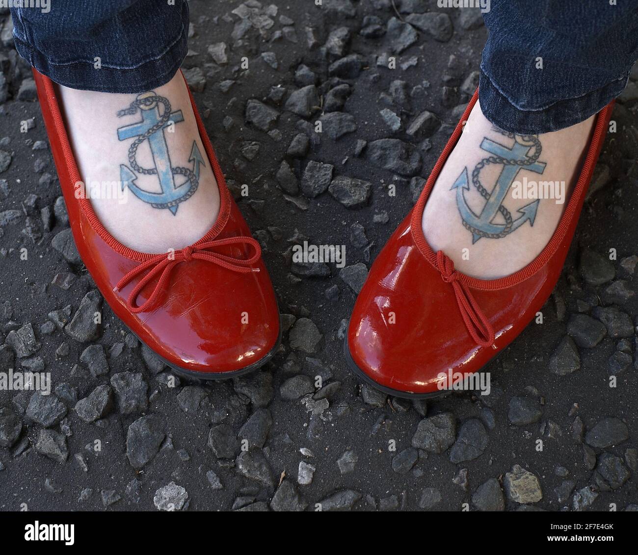 Gros plan des pieds femelles avec des tatouages d'ancre portant des plats de ballet brevetés . Banque D'Images