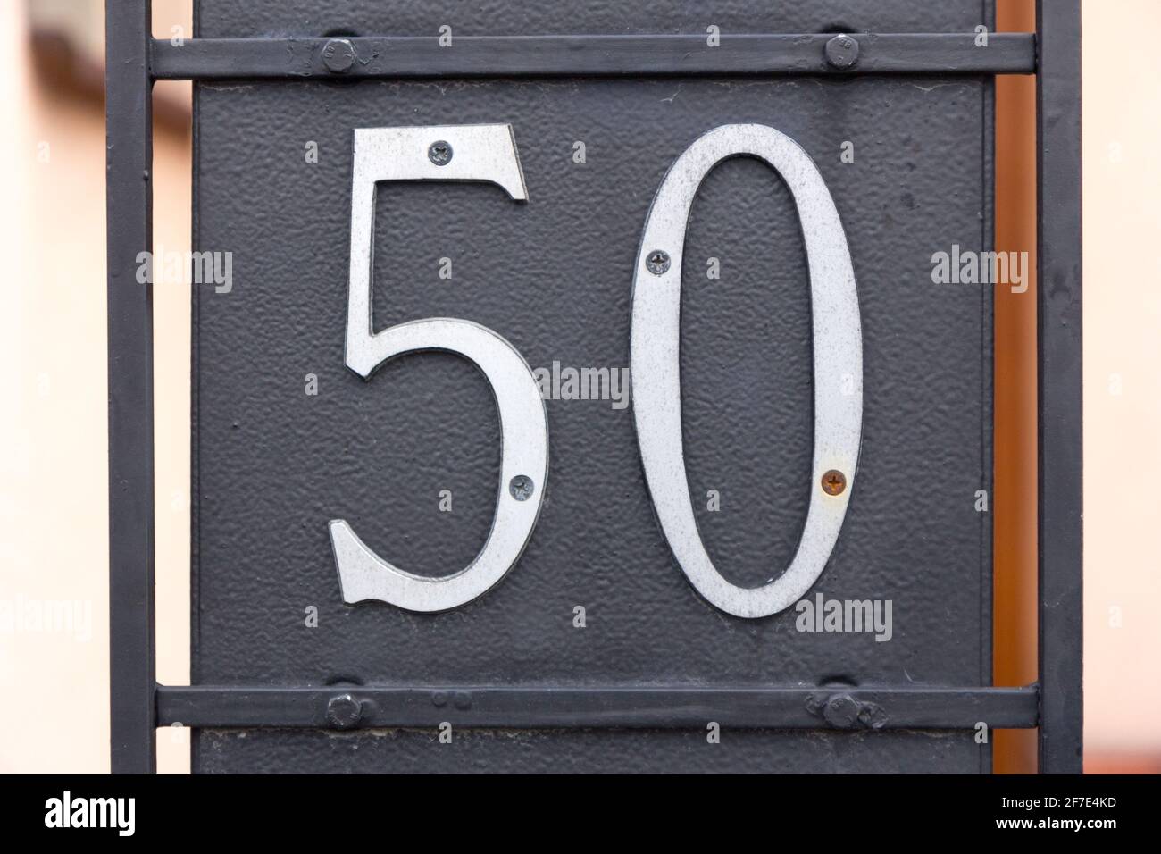 Le numéro 50 (cinquante) en métal vissé sur un noir plaque métallique Banque D'Images