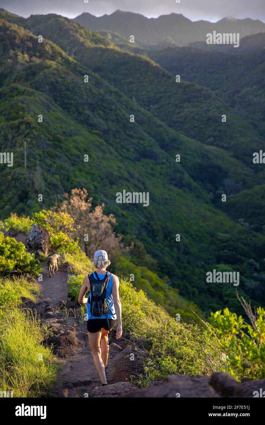 Femme intrépide et son chien marchant le long d'un sentier étroit À Hawaï Banque D'Images