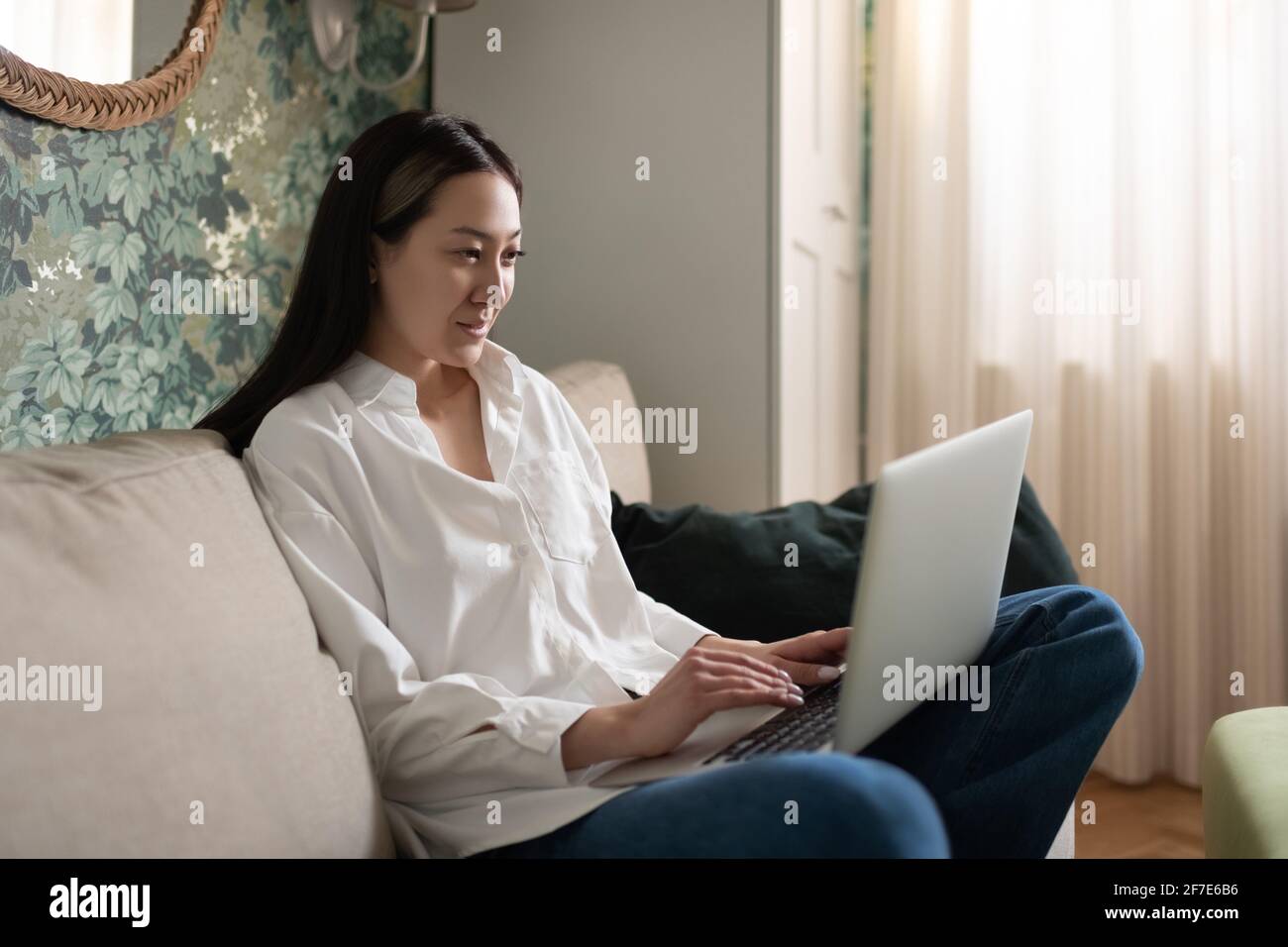 Asian woman using laptop on sofa Banque D'Images