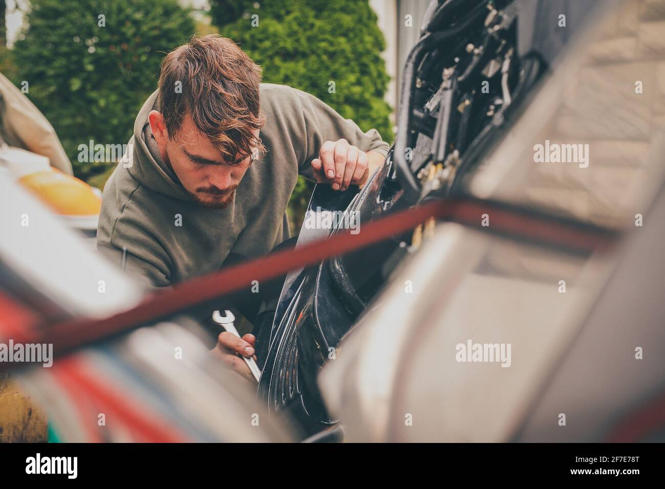 Un jeune homme caucasien déchirant un moteur hors-bord dans le cadre d'une opération d'entretien sur un moteur. Atelier pour moteurs hors-bord. Banque D'Images