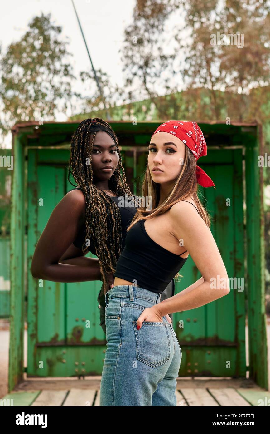 Deux femmes multiethniques en vêtements urbains posent regarder le appareil photo Banque D'Images