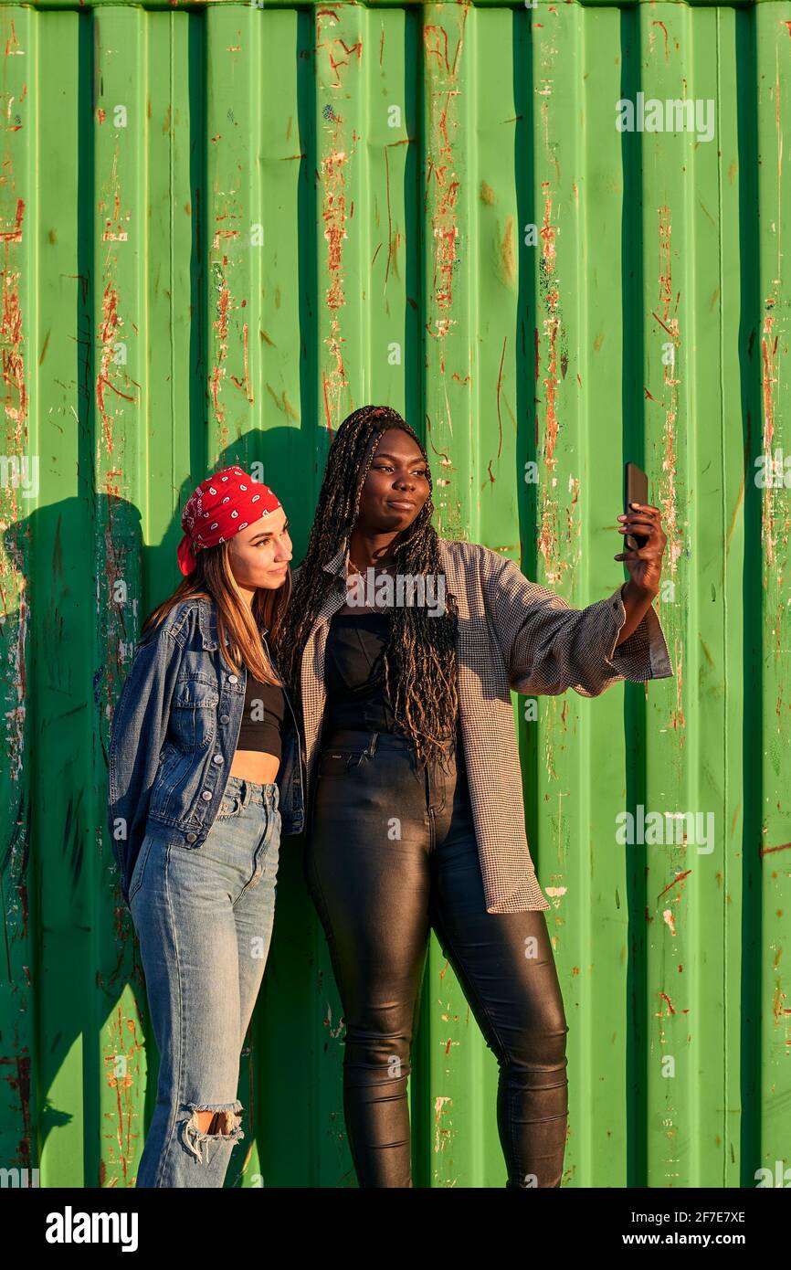 Deux femmes multiethniques en vêtements urbains prennent une photo avec un téléphone Banque D'Images
