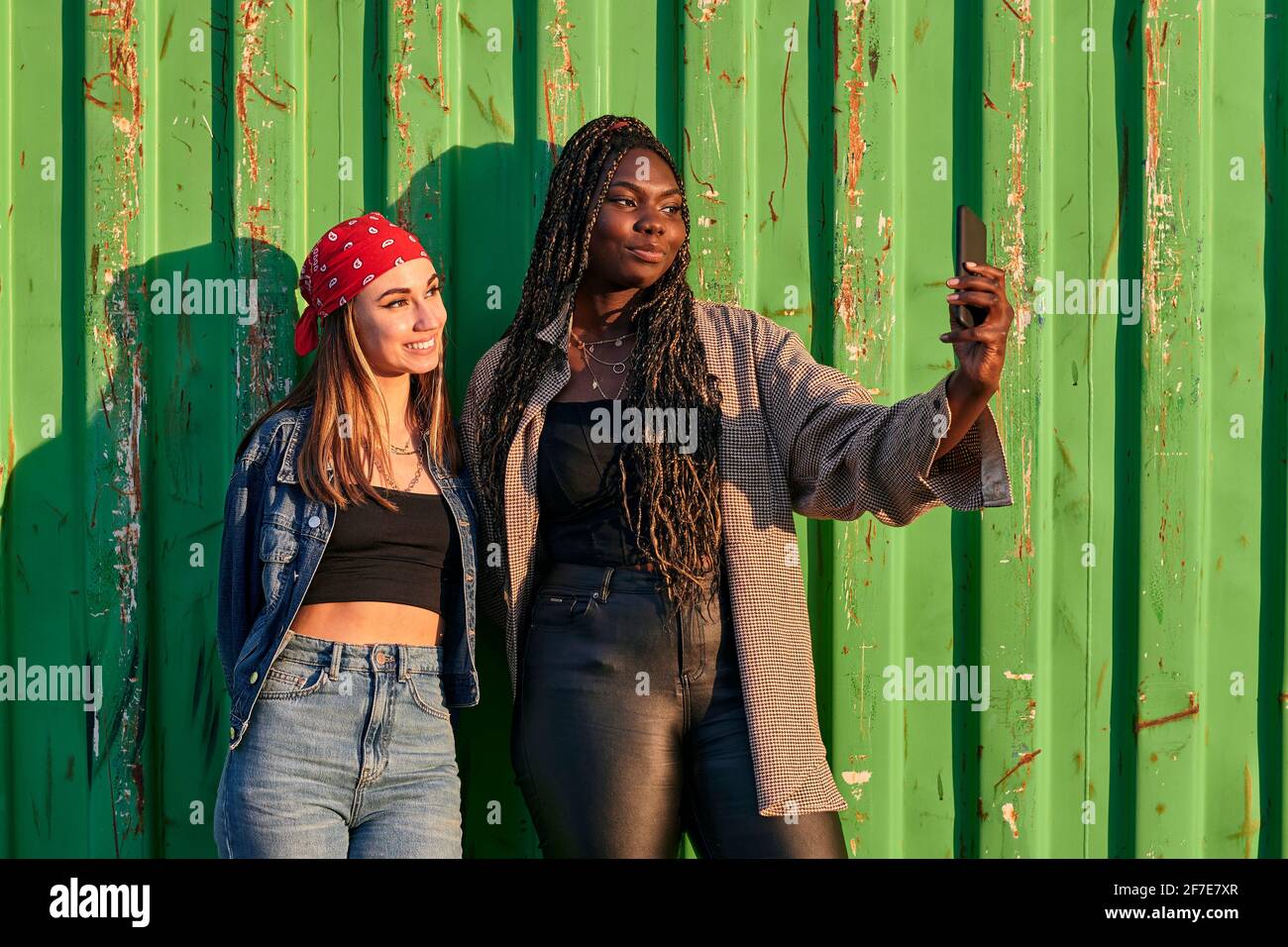 Deux femmes multiethniques en vêtements urbains prennent une photo avec un téléphone Banque D'Images
