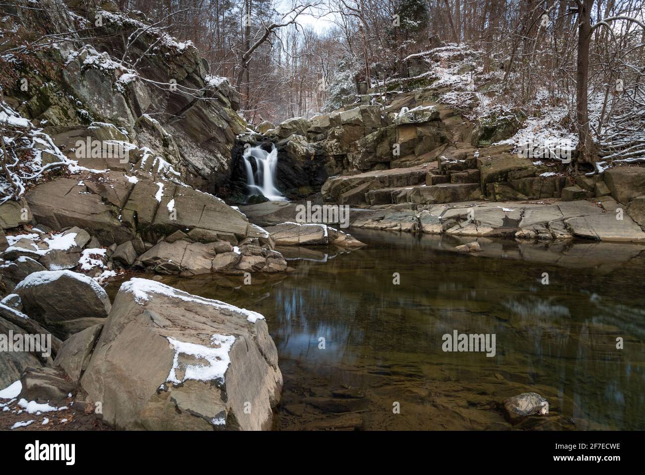 La chute d'eau de la réserve naturelle Scott's Run en Virginie du Nord sous un ciel nuageux l'après-midi d'hiver avec une légère accumulation de neige sur les rochers. Banque D'Images