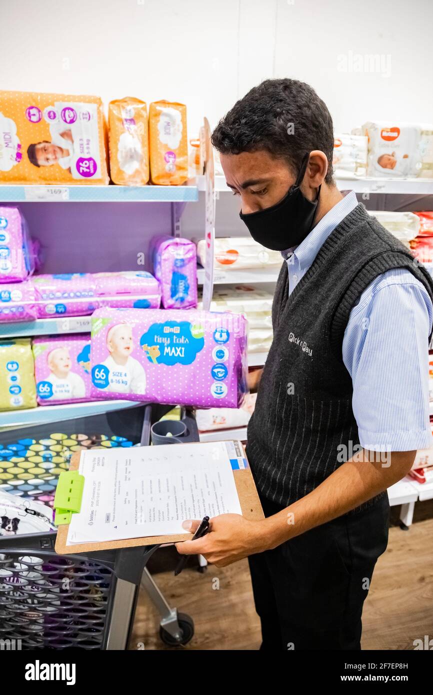 Cape Town, Afrique du Sud - 10 décembre 2020 : membre du personnel qui cueille les produits d'épicerie de l'étagère pour un service de livraison express à domicile au service local Pick n Pay su Banque D'Images