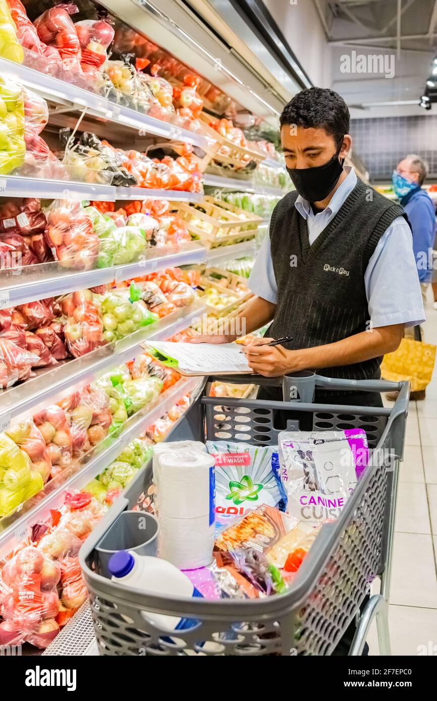 Cape Town, Afrique du Sud - 10 décembre 2020 : membre du personnel qui cueille les produits d'épicerie de l'étagère pour un service de livraison express à domicile au service local Pick n Pay su Banque D'Images