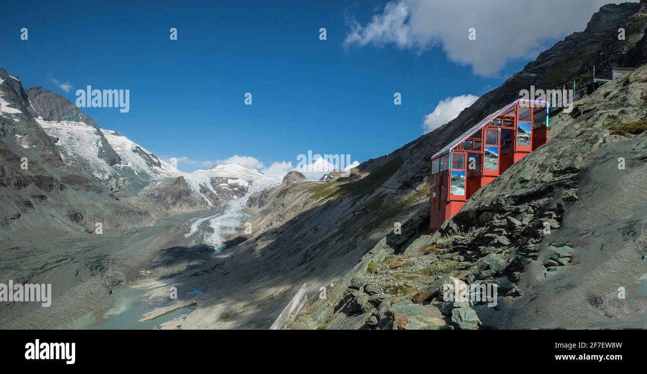 Funiculaire rouge sur la chaîne de montagnes Grossglockner, juste derrière le glacier de Pasterze en arrière-plan, par une chaude journée ensoleillée avec un ciel bleu dans le summe Banque D'Images