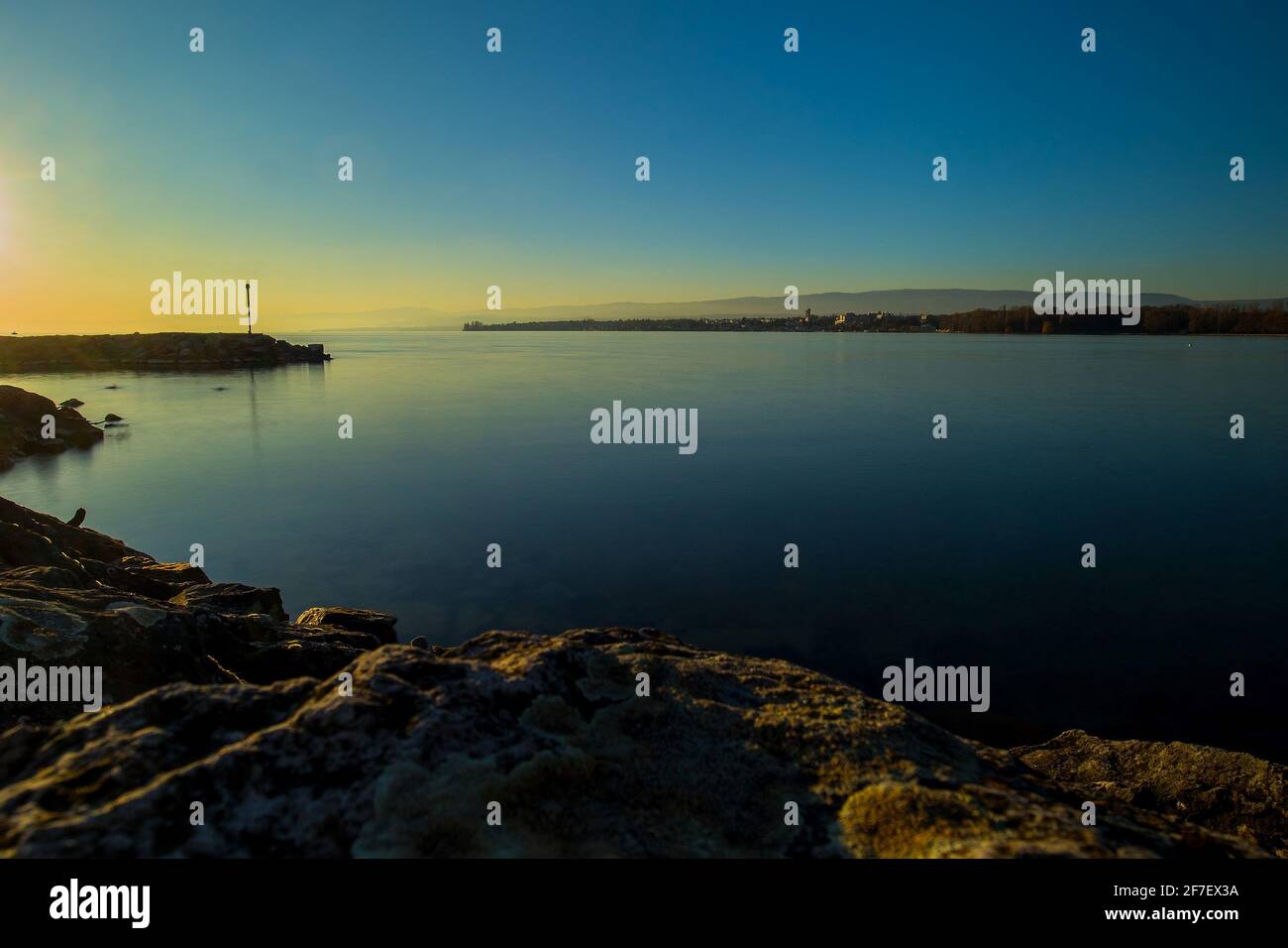 Belle soirée photo du lac Léman près de Lausanne, avec soleil juste au-dessus de l'horizon et longue exposition à l'eau. Banque D'Images