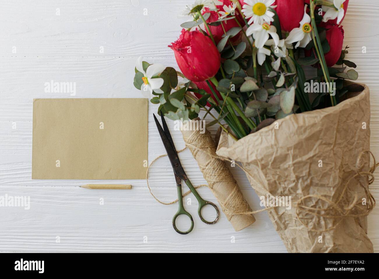 Bonne journée des mères. Bouquet élégant de tulipes rouges, jonquilles et  eucalyptus en papier artisanal avec carte de vœux, crayon, ciseaux et  ficelle sur blanc rustique Photo Stock - Alamy