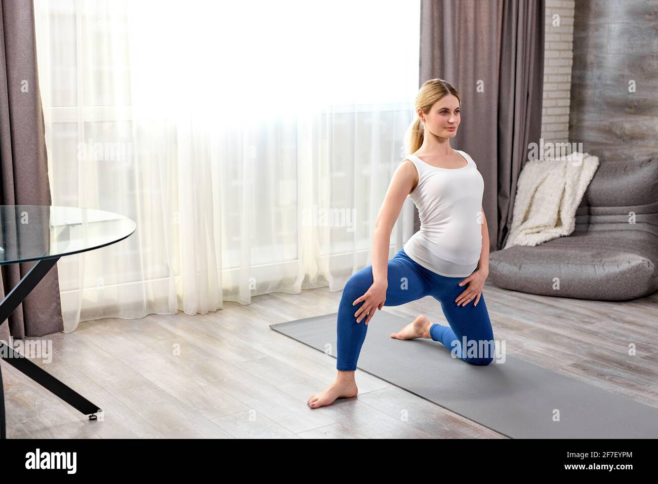 calme futur maman-à-être, femme enceinte dans des vêtements de sport  faisant des exercices sur le tapis de fitness, les jambes étirant, la  flexibilité de train, à la maison. yoga, sain Photo Stock -