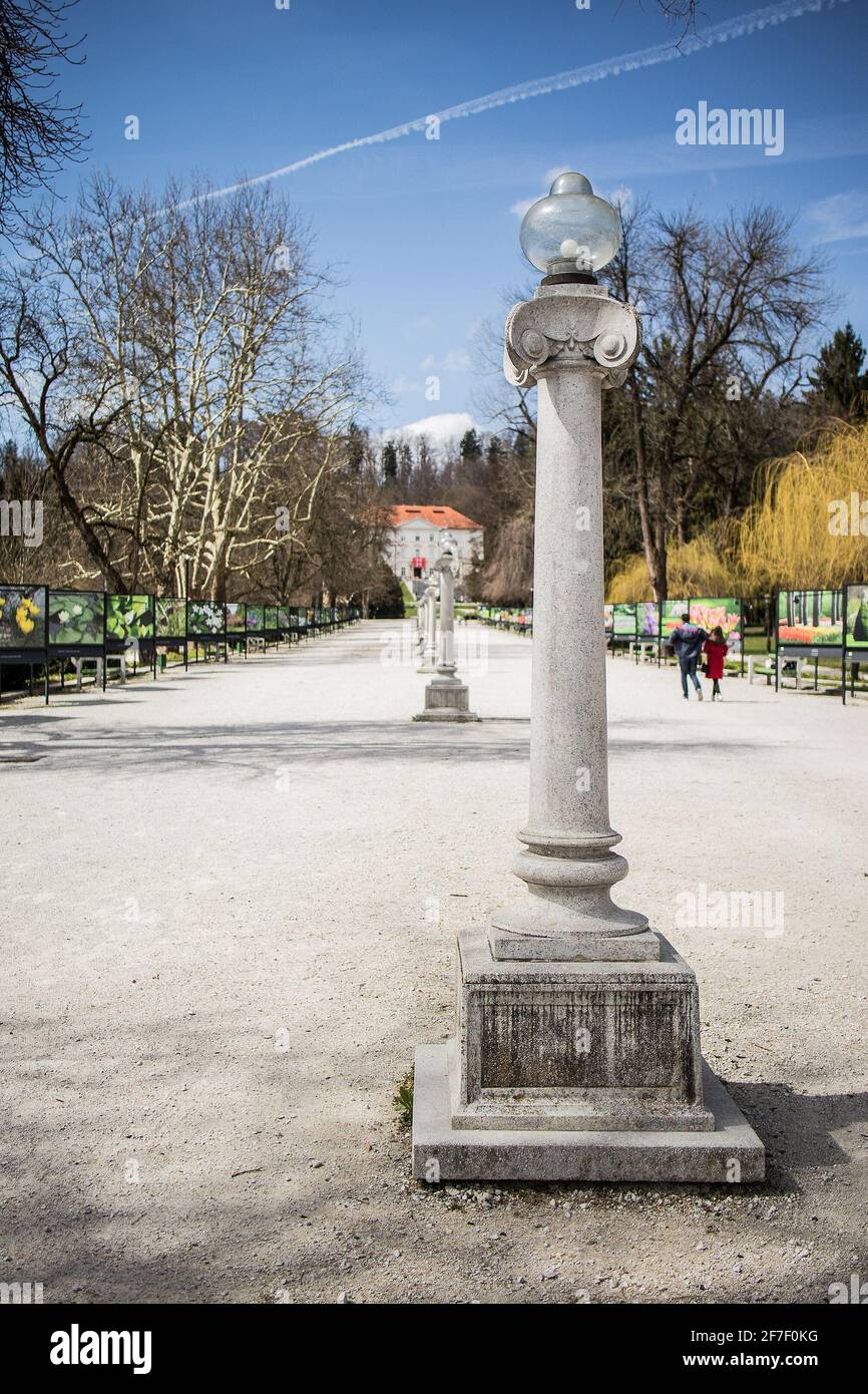 Jakopicevo strehajalisce, une passerelle dans le parc Tivoli ou les jardins de ljubljana avec des lumières de rue millésimes et un château en arrière-plan. Banque D'Images