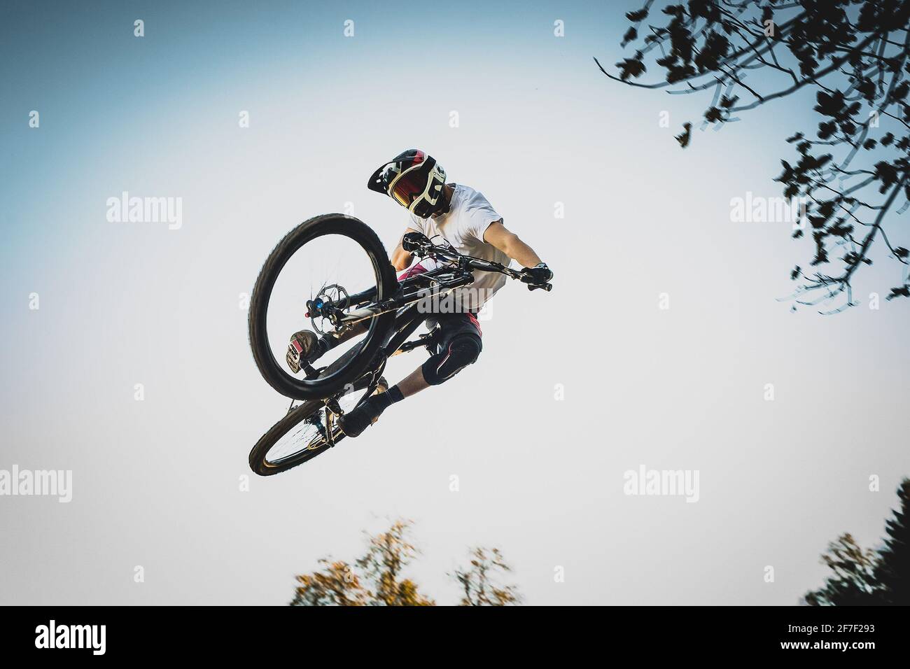 Photo frontale d'un motard de montagne sautant au-dessus d'un saut de terre dans un parc de vélo exécutant un fouet de queue . Banque D'Images