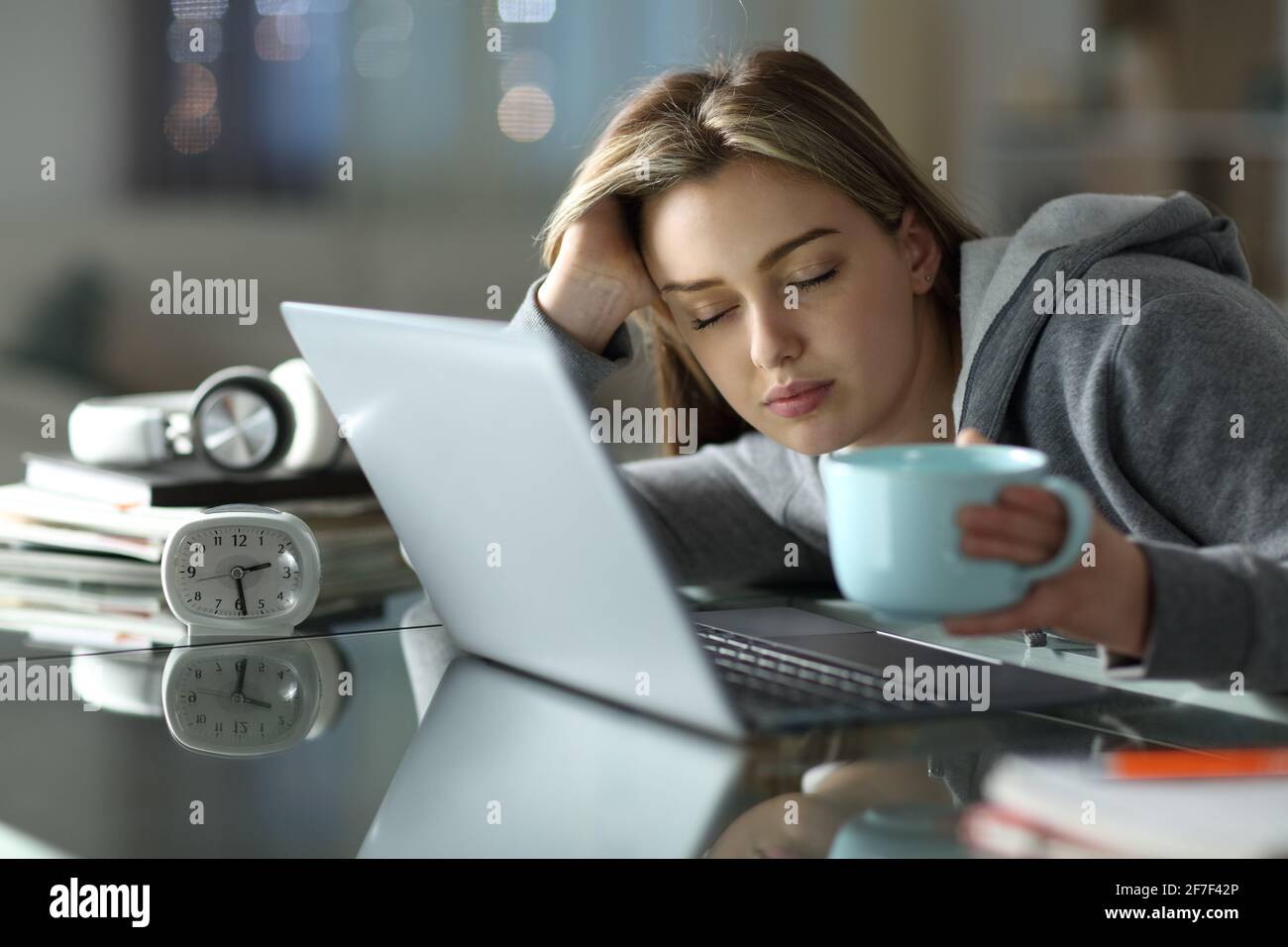 Un étudiant endormi et fatigué travaillant avec un ordinateur portable la nuit à la maison Banque D'Images