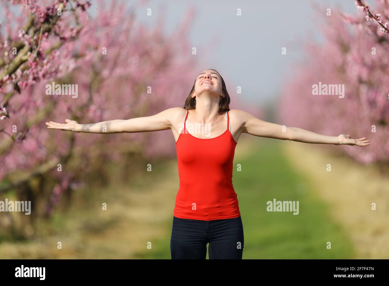 Portrait d'une femme excitée célébrant les étirements du printemps bras dans un champ fleuri Banque D'Images