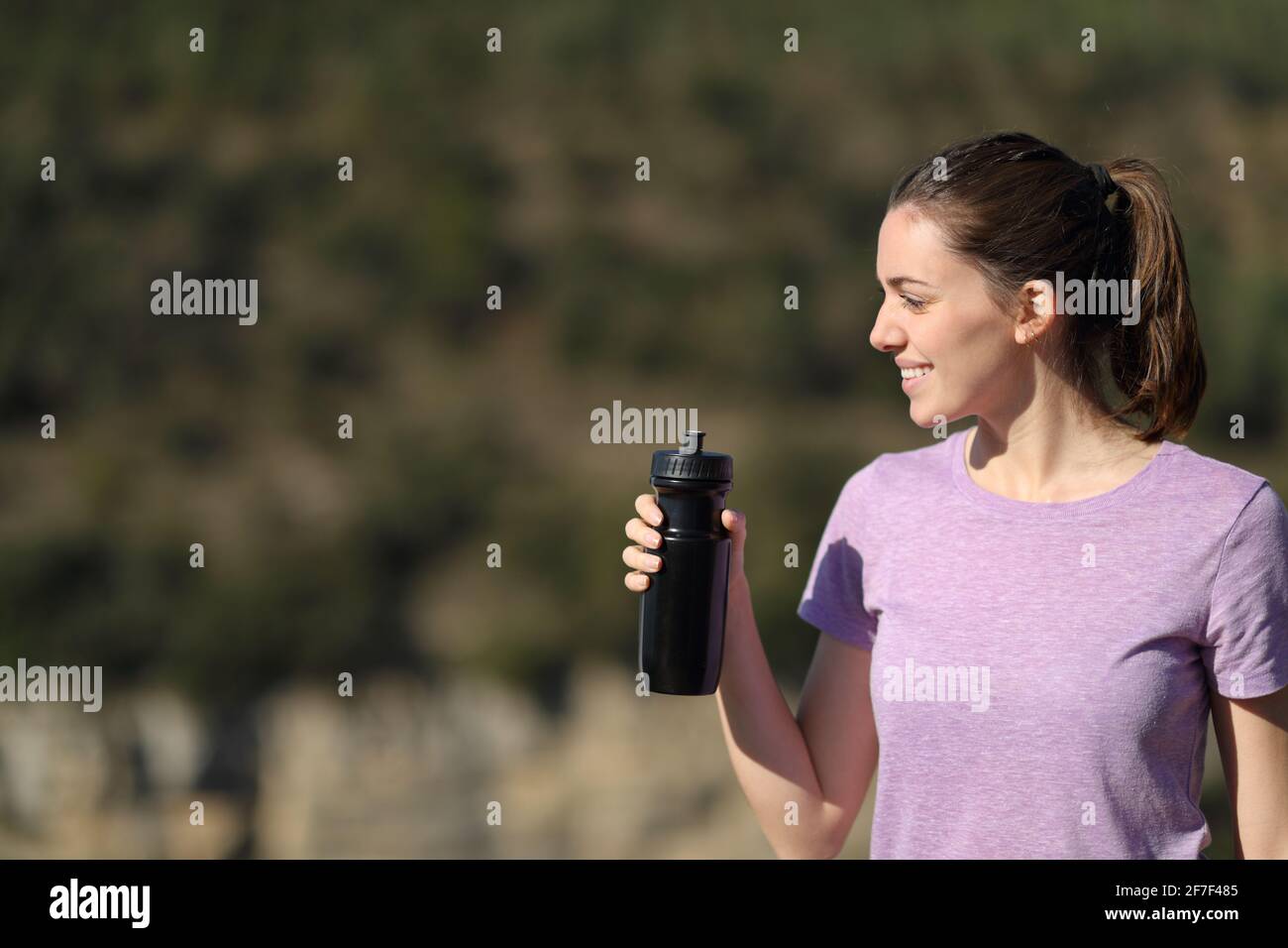 Joli jogger tenant une bouteille d'eau pour contempler la vue dans le montagne Banque D'Images
