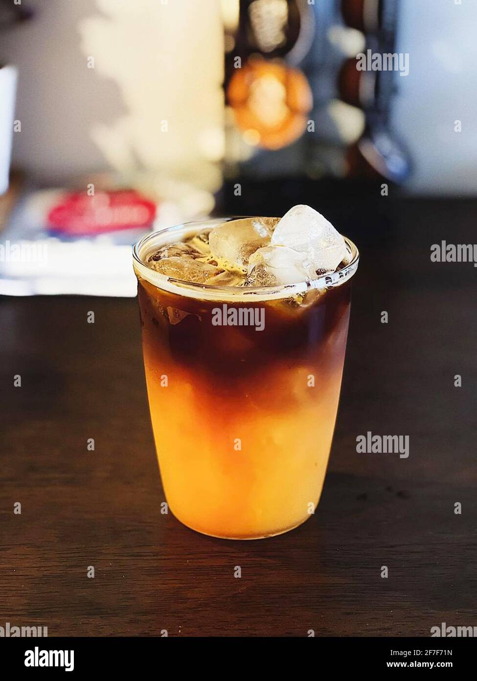Café glacé à l'orange - UN verre en plastique d'americano mélangé avec du soda artisanal et du jus d'orange yuzu sur fond flou, boisson rafraîchissante conc d'été Banque D'Images