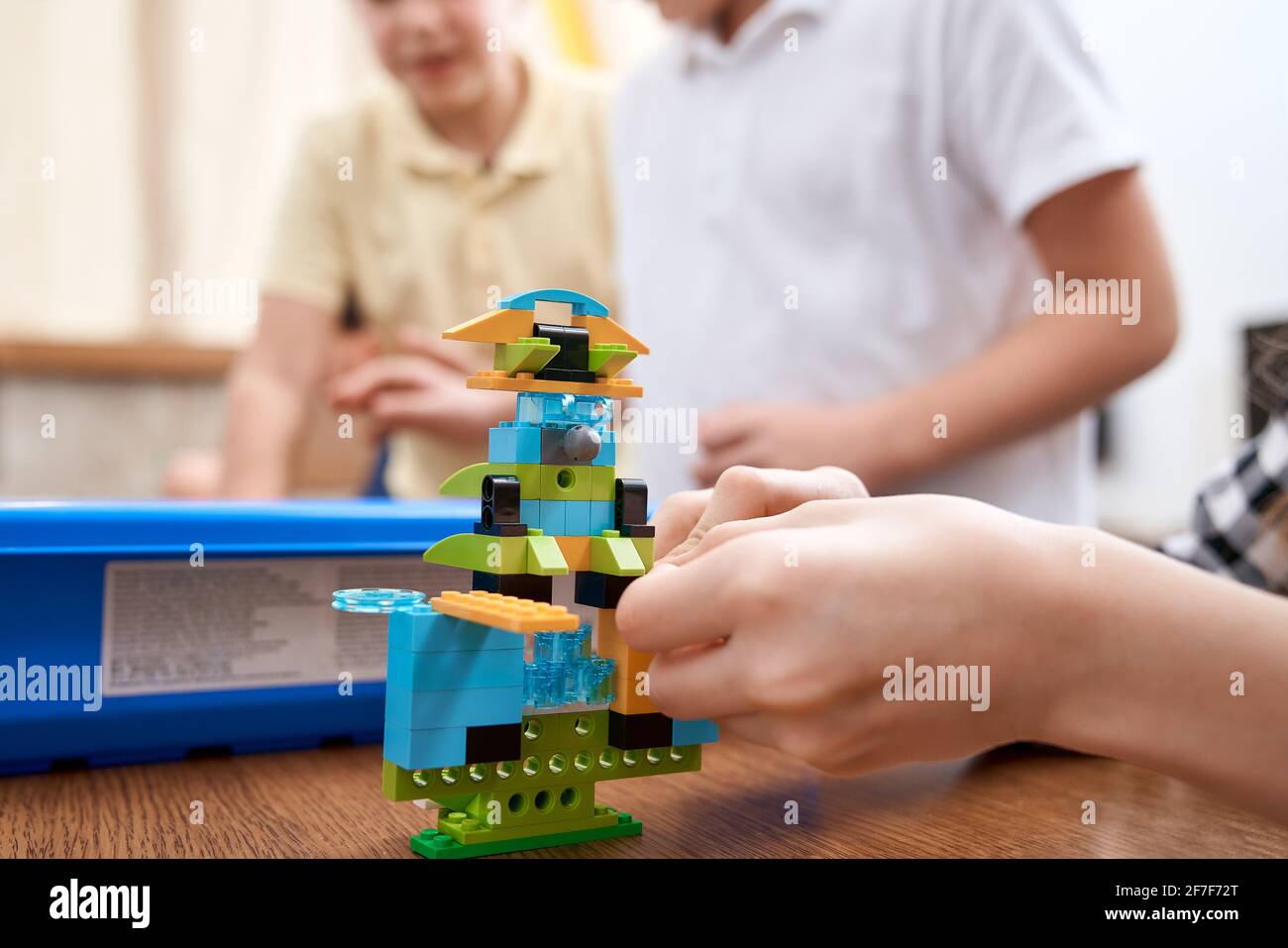 Concentration sélective des mains en utilisant le kit de construction pour les enfants, la création de jouets. Récolte d'enfant incognito caucasien travaillant sur le projet, prenant des parties colorées. Concept de génie scientifique. Banque D'Images