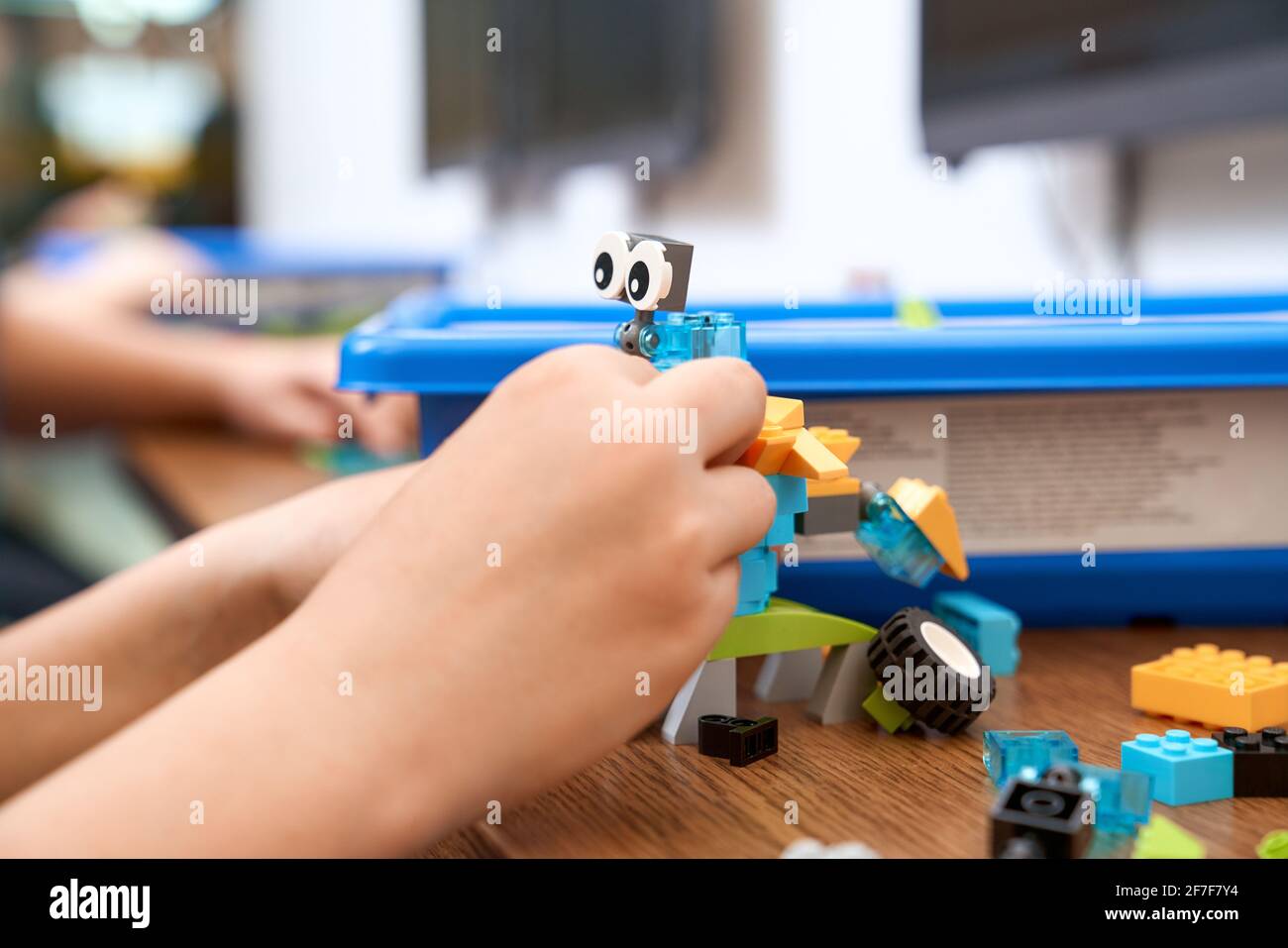 Concentration sélective des mains en utilisant le kit de construction pour les enfants, la création de jouets. Récolte d'enfant incognito caucasien travaillant sur le projet, prenant des parties colorées. Concept de génie scientifique. Banque D'Images