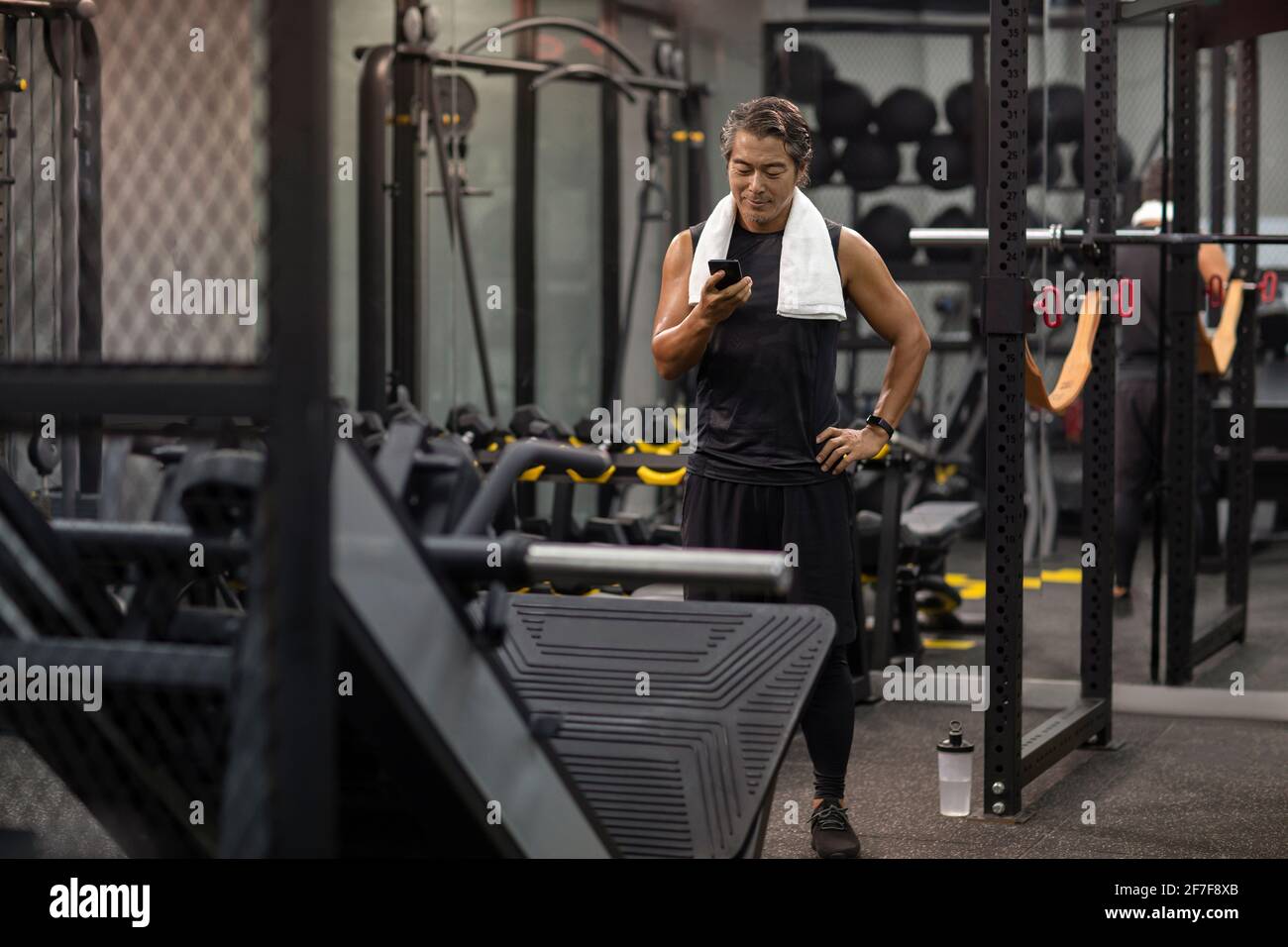 Homme mature utilisant un smartphone à la salle de gym Banque D'Images
