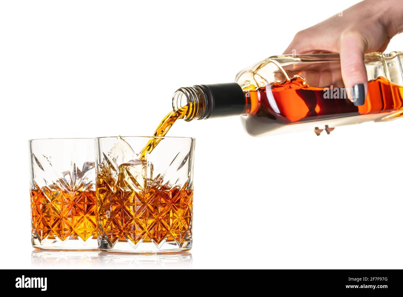 le whisky est versé dans un verre de la bouteille sur blanc arrière-plan isolé Banque D'Images