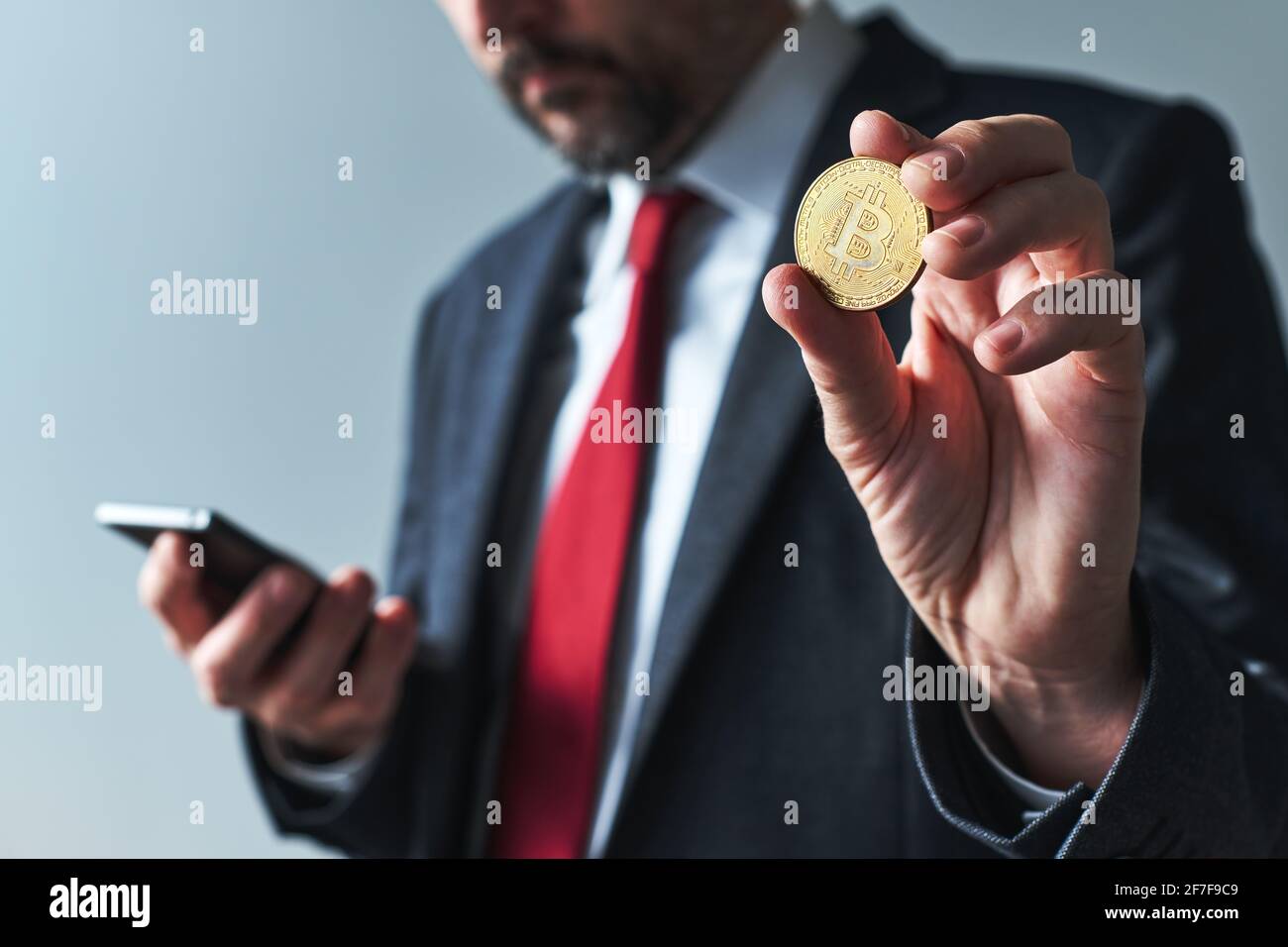 Homme d'affaires utilisant l'application mobile pour smartphone pour l'exploitation minière Bitcoin, gros plan avec une attention sélective Banque D'Images