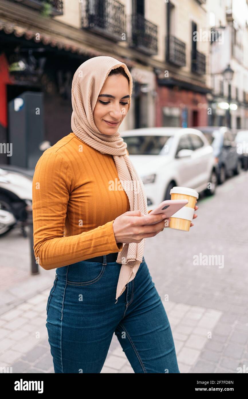 Jolie jeune femme musulmane portant un foulard à l'aide de son téléphone  portable et marchant dans la ville Photo Stock - Alamy