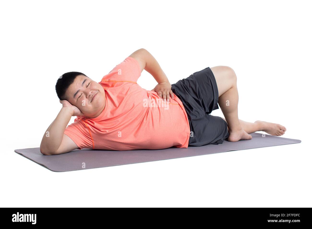 Un jeune homme en surpoids allongé sur un tapis d'exercice Banque D'Images