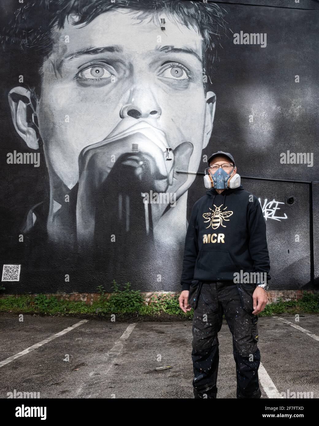 Akse, artiste de rue, se dresse devant sa fresque de Ian Curtis, le leader de Joy Division. Banque D'Images