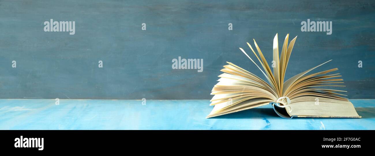 ouvrez le livre sur fond sombre. Lecture, littérature, éducation, bibliothèque, bureau à domicile, concept de rentrée scolaire, foyer sélectif, panoramique, bon espace de copie Banque D'Images