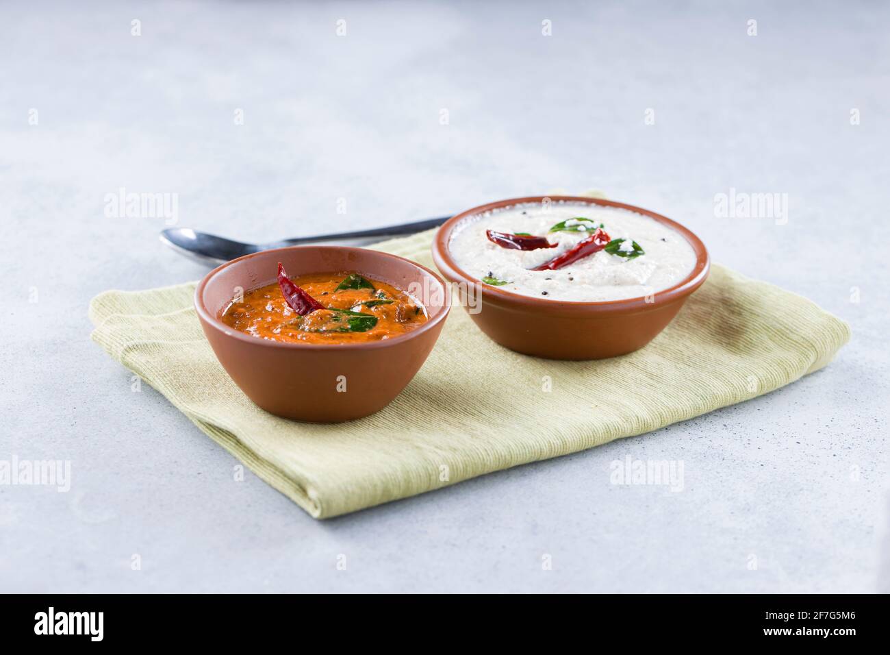 Chutney chutney de noix de coco blanc et chutney d'oignons disposés dans une serviette placée sur un fond texturé gris. Banque D'Images