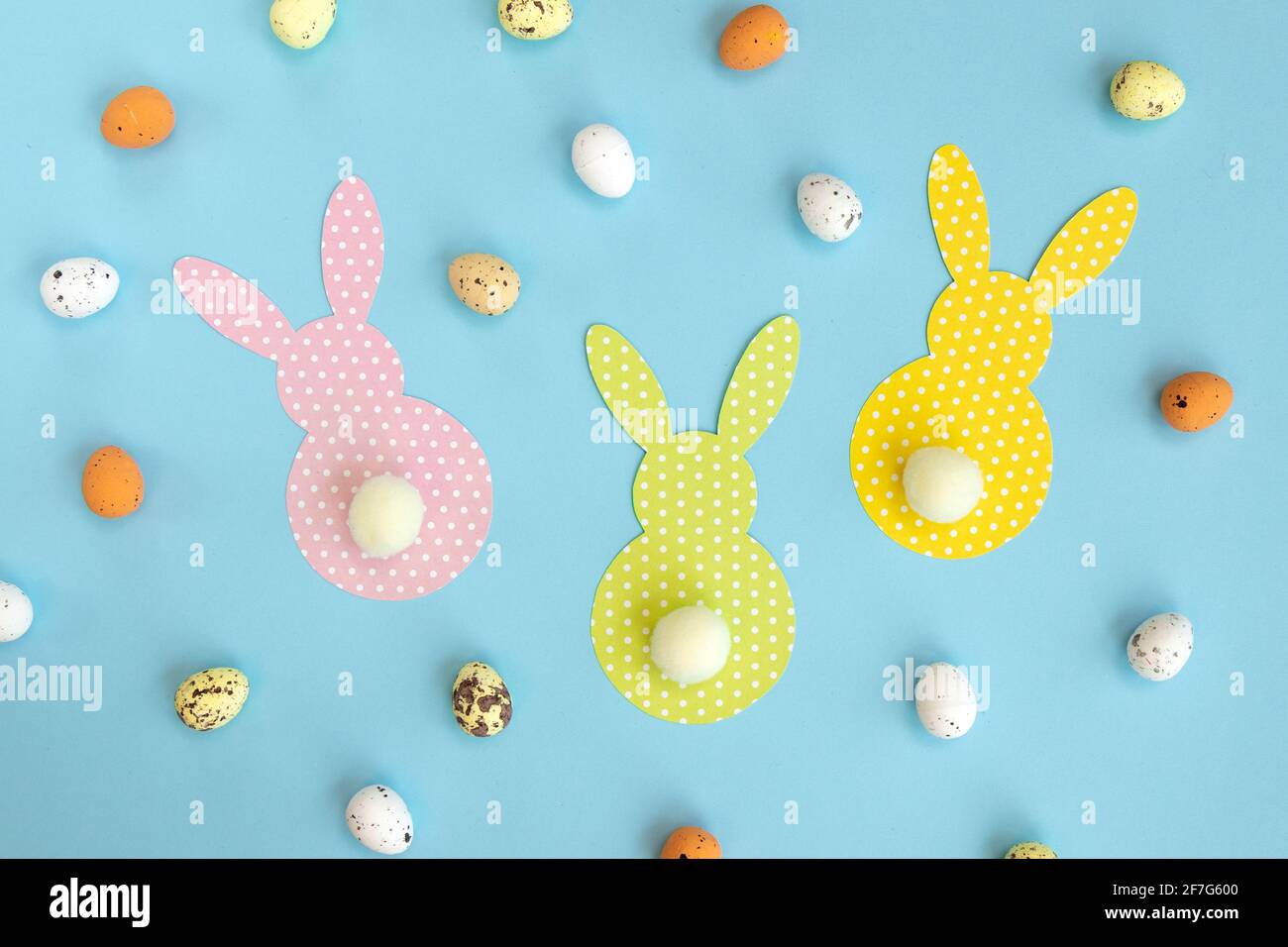 Lapins en papier de Pâques isolés sur fond bleu. Bricolage vacances artisanat décoration de lapins colorés. Concept: Artisanat pour les enfants pour Pâques. Haut vi Banque D'Images