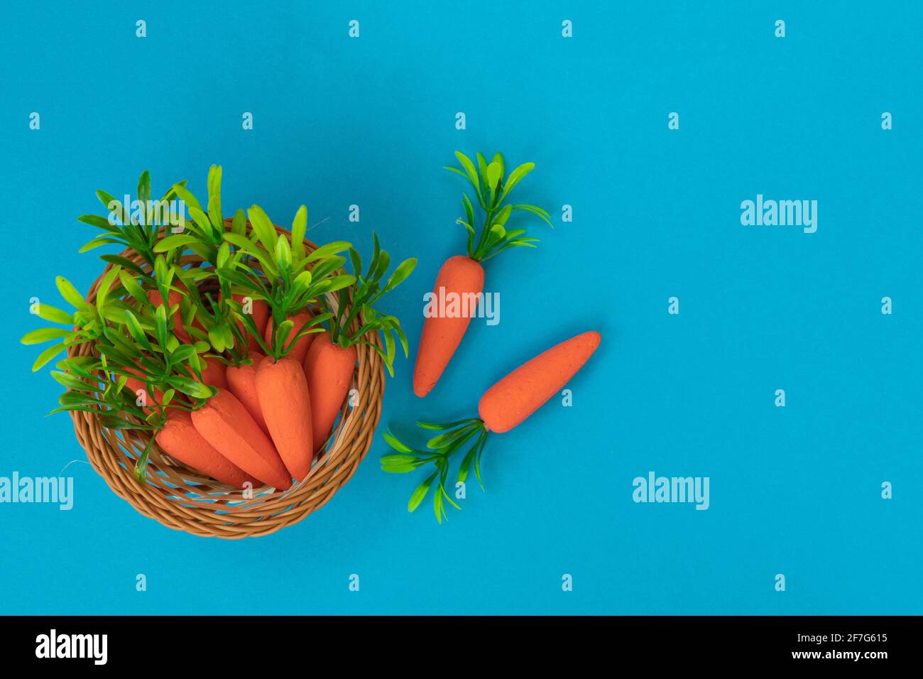 Motif Pâques fait avec des carottes sur fond bleu. Composition de Pâques minimale. Pose à plat. Banque D'Images