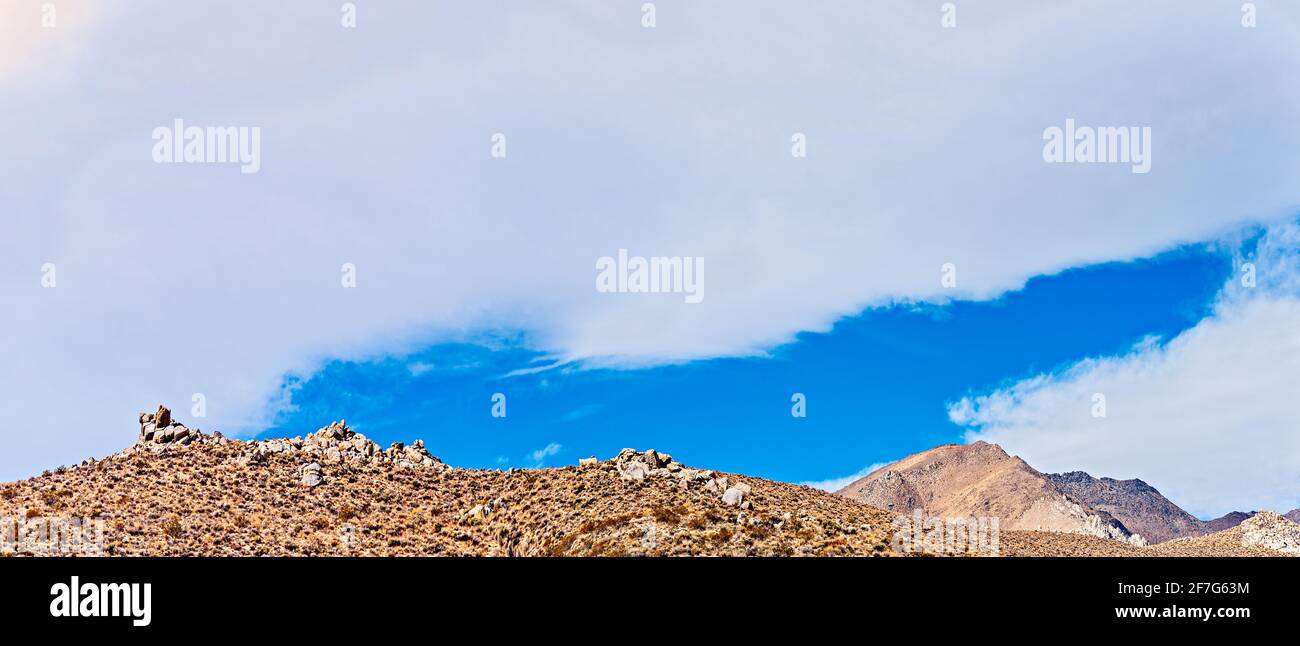 Flanc de coteau rocheux sous ciel bleu avec nuages blancs Banque D'Images