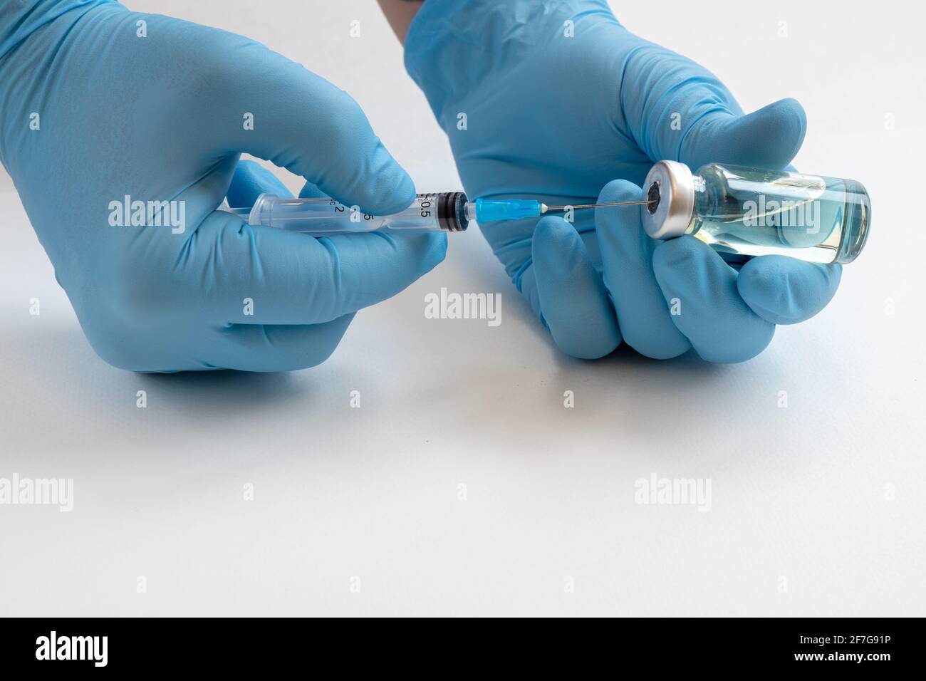 Main du médecin tenant le flacon de médicament et la seringue pour le vaccin au patient sur fond blanc. Immunisation traitement de la grippe concept de vaccination. Banque D'Images