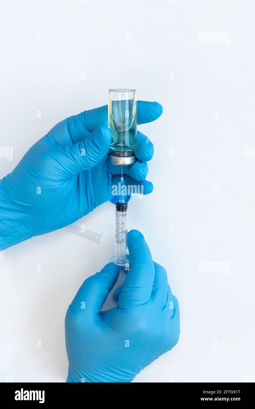 Main du médecin tenant le flacon de médicament et la seringue pour le vaccin au patient sur fond blanc. Vaccination coronavirus traitement de la grippe conce de vaccination Banque D'Images