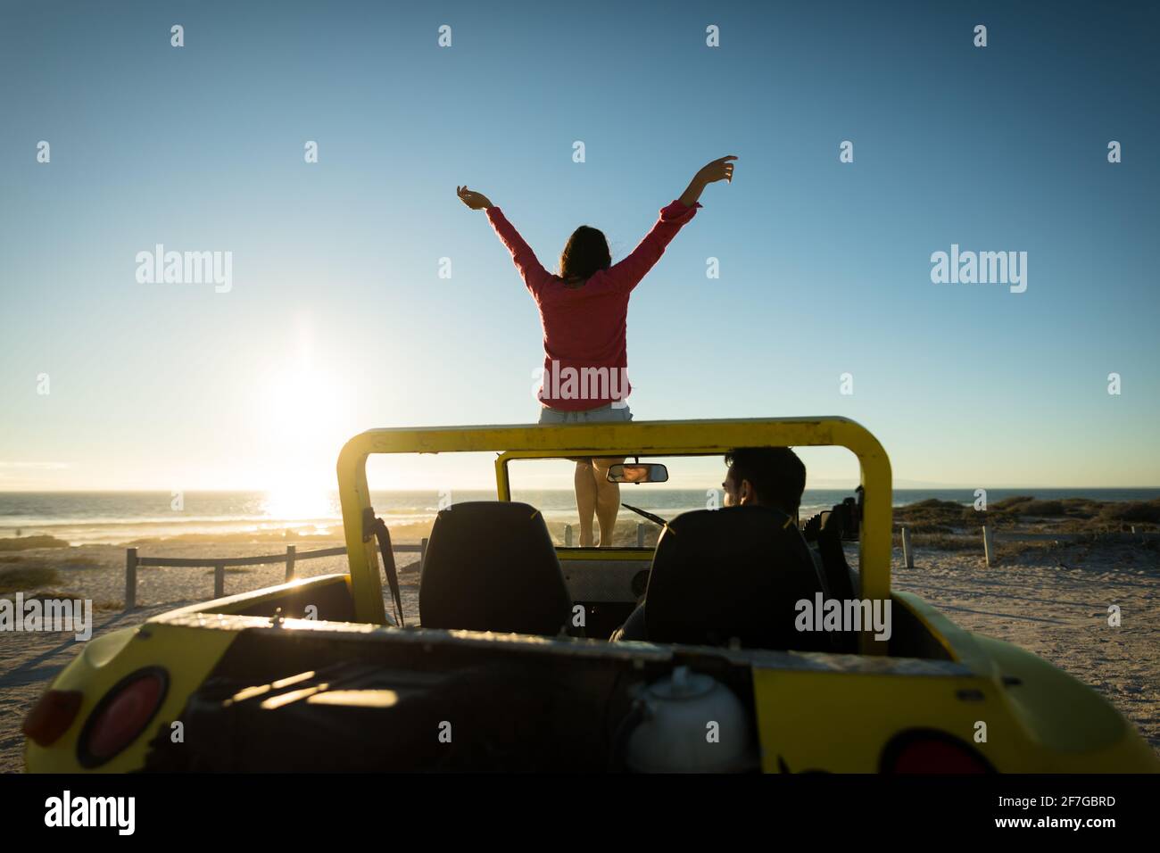 Couple caucasien heureux sur la plage pendant le coucher du soleil femme assise sur bonhomme de plage assis Banque D'Images