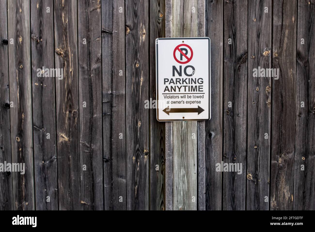 Un panneau vertical et rectangulaire en forme de no parking Anytime est placé sur une clôture en bois abîmé à London, Ontario, Canada, février 2021. Banque D'Images