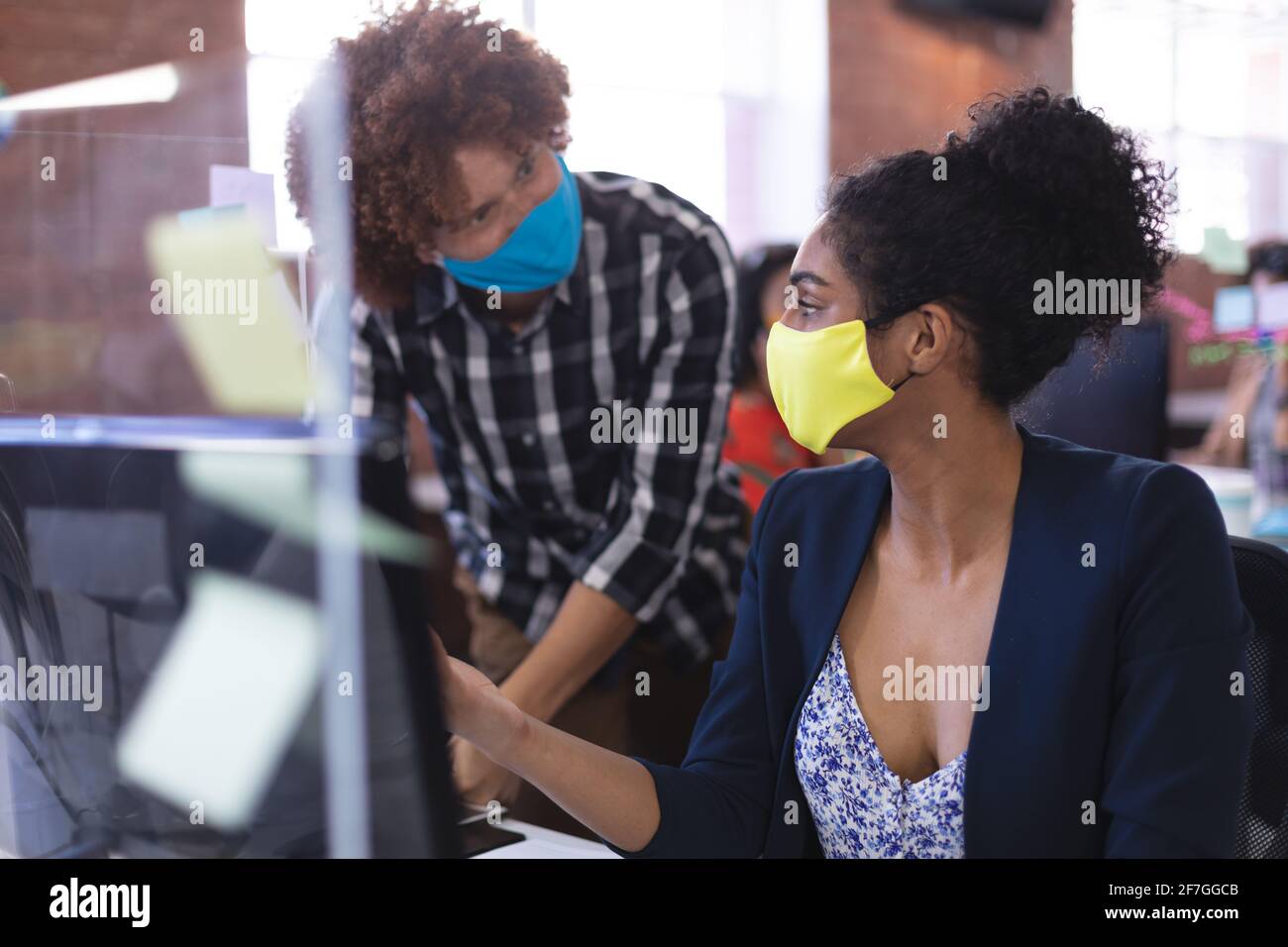 Race mixte mâle et femelle portant des masques dans la discussion à travail Banque D'Images