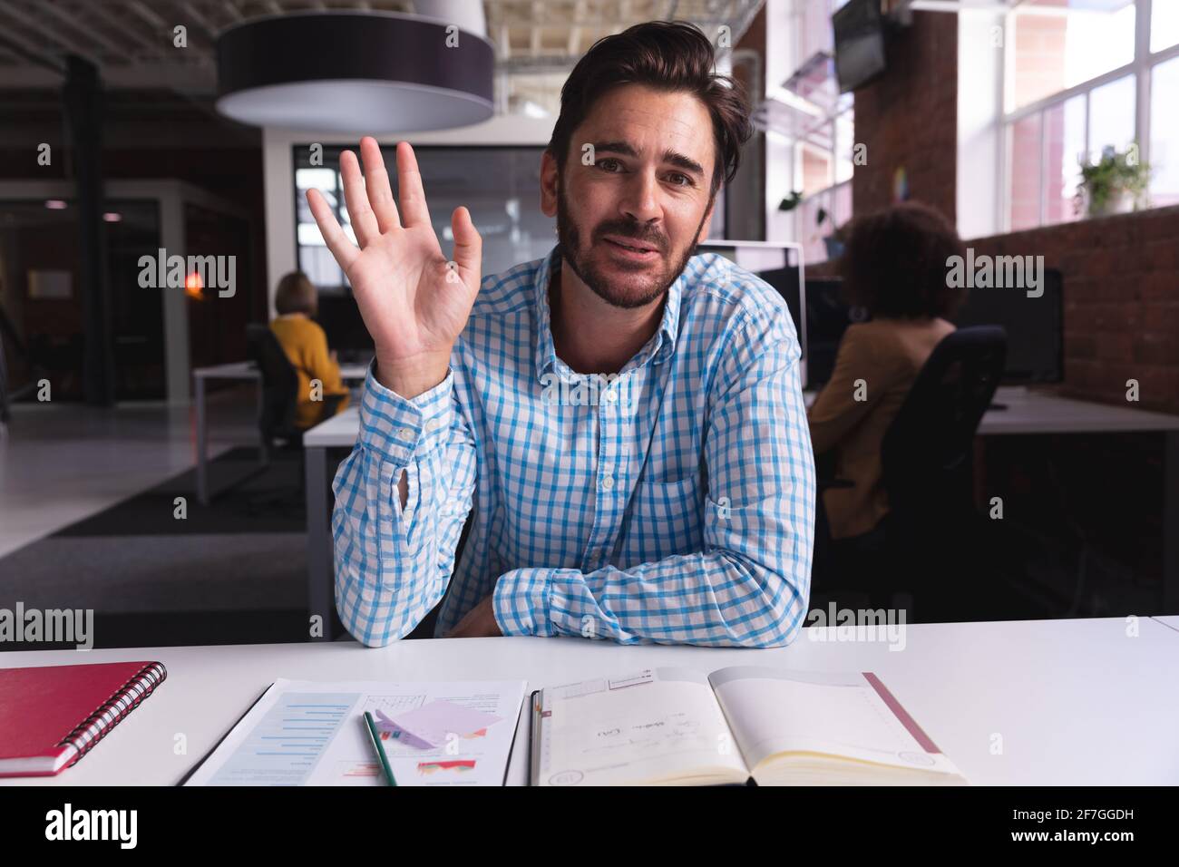 Homme d'affaires caucasien assis à la réception avec des documents disant bonjour avoir appel vidéo Banque D'Images