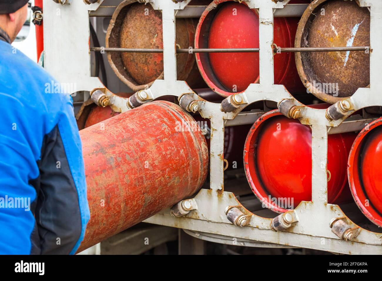 Un travailleur industriel masculin dépose une bouteille de gaz dans une machine à gaz. Équipement pour le transport sécuritaire des bouteilles de propane. Banque D'Images