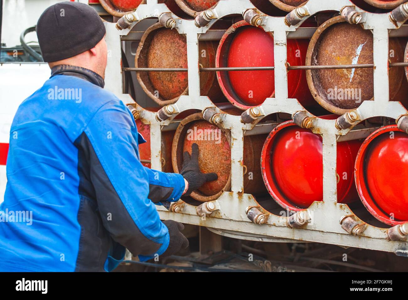 Un travailleur industriel masculin dépose une bouteille de gaz dans une machine à gaz. Équipement pour le transport sécuritaire des bouteilles de propane. Banque D'Images
