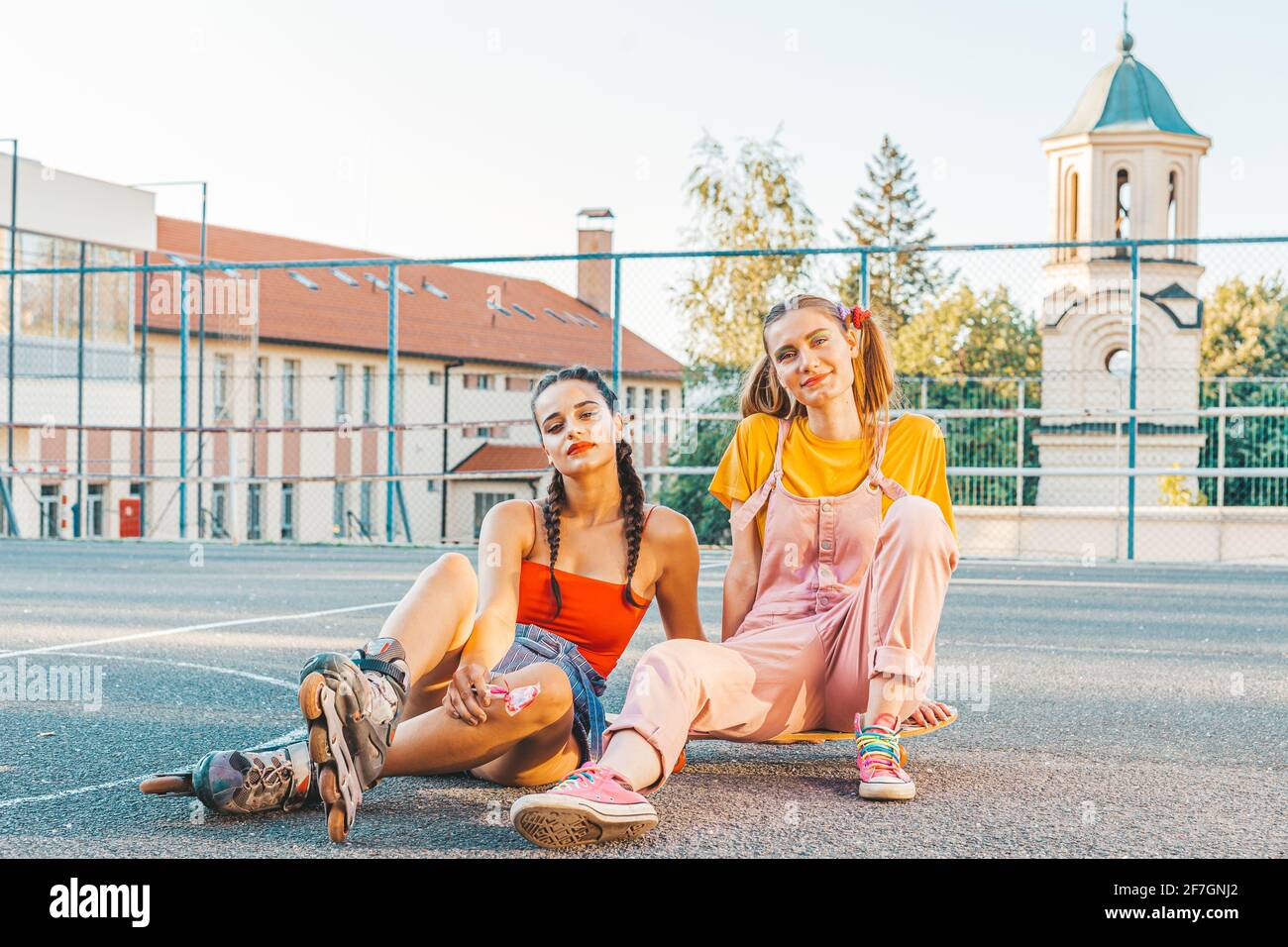 Deux filles adolescentes, amis en vêtements colorés avec patins à roulettes et planche à roulettes. Style urbain Banque D'Images