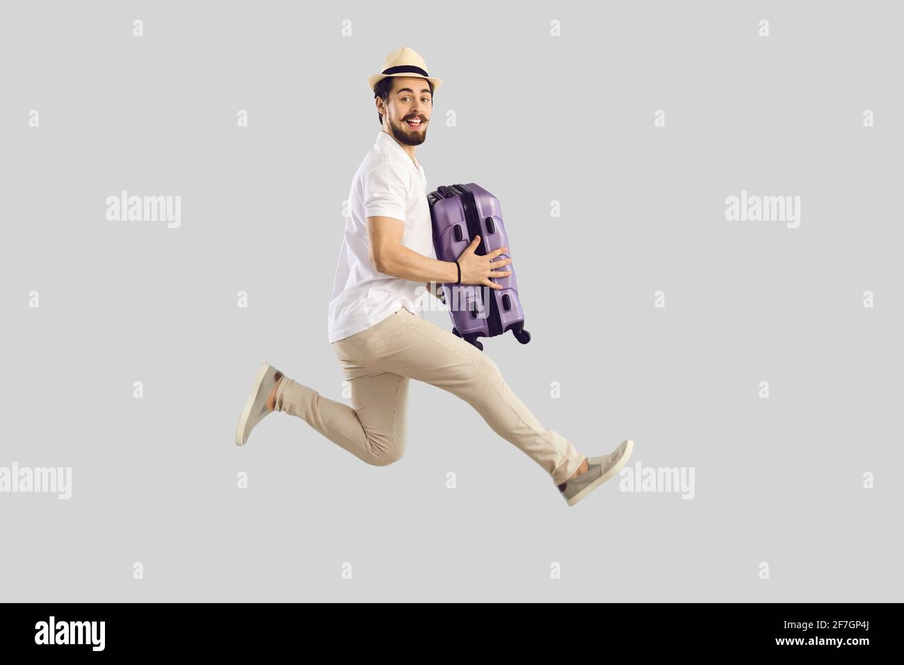 Un homme de tourisme enthousiaste en été, un chapeau sautant avec des valises portrait de studio Banque D'Images