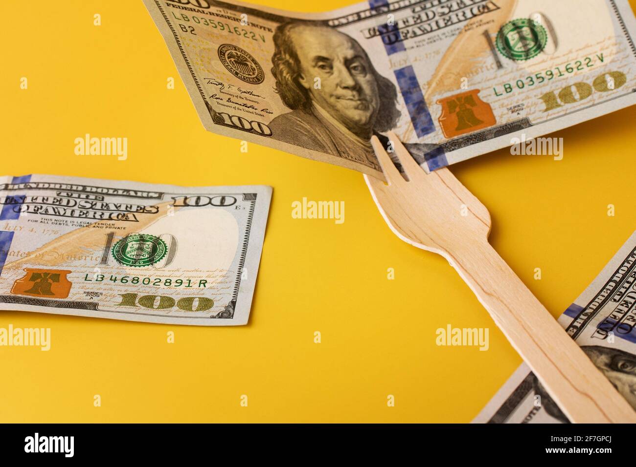 Des billets de cent dollars sur une fourchette en bois. Ustensile écologique naturel. Contexte du concept d'entreprise Banque D'Images