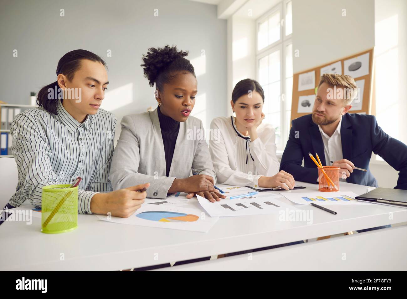 Équipe de jeunes entrepreneurs travaillant avec des documents et discutant plus loin stratégie commerciale Banque D'Images